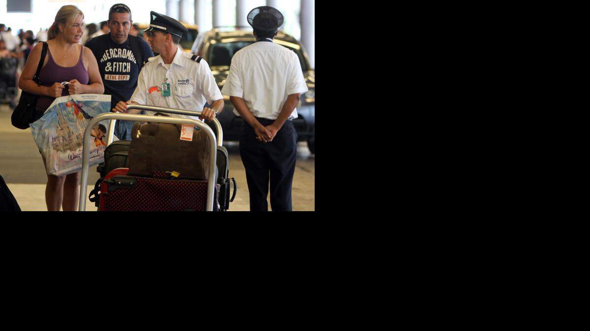 
A Eulen America employee helps passengers with their bags at Miami International Airport in 2010.
