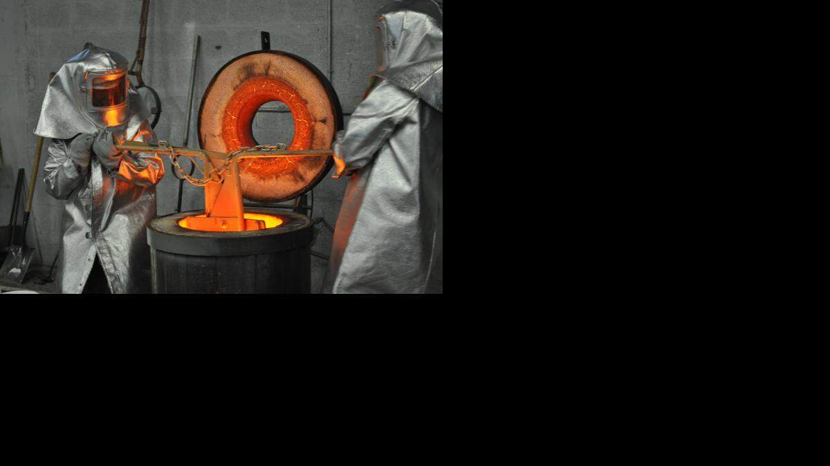 
Two workers melt bronze.
