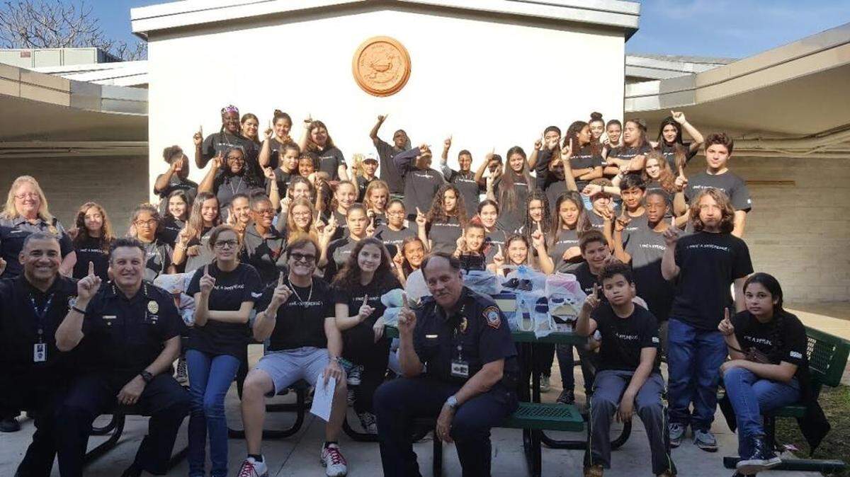 Students from the South Miami Middle School club The Power of One pose with South Miami police officers before donating more than 50 pairs of shoes to students at Ludlum Elementary.