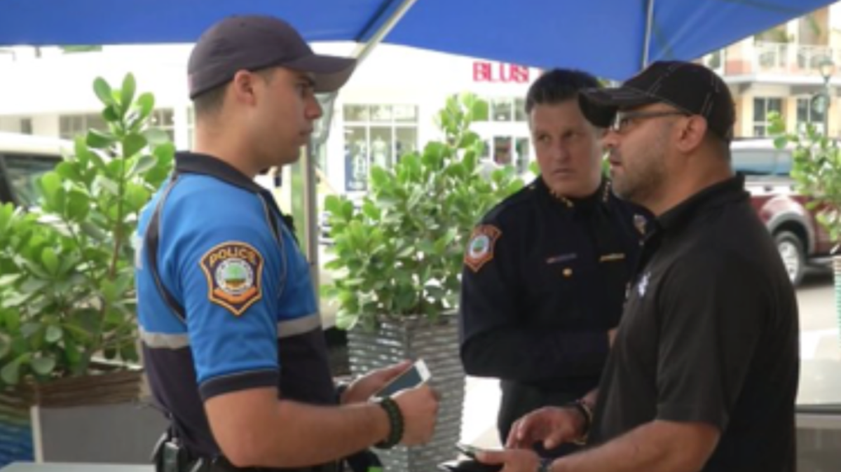 Officer Serguey Hernandez, left, speaks with South Miami Police Chief Rene Landa, center.
