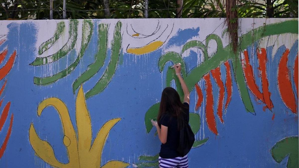 A volunteer helps ArtSouth, a not-for-profit organization, during their international service learning mural-completion project at the Gibson-Bethel Community Center in South Miami on Tuesday, Aug. 2, 2016.