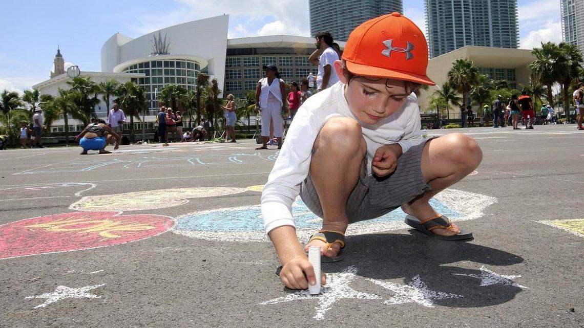 
Giovanni Grandinetti, 7, of Miami, chalks in stars on the blacktop behind AmericanAirlines Arena during Engage Miami's Chalk-athon on Saturday, Aug. 8, 2015. An organization created to engage young Miamians on local issues, Engage Miami hosted the free event to help transform Parcel B into the park of their dreams: Dan Paul Park. More than 20 years ago, the people of Miami were promised by Miami-Dade County and the Miami Heat that the four acres of land behind the arena would be a waterfront park for the public. The park went undeveloped and the parcel was paved with asphalt earlier this year. Several community organizations participated in the event, open to the public.
