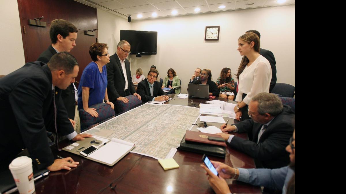 
Florida Department of Transportation (FDOT) officials discuss plans with Miami-Dade Commissioners Rebeca Sosa (center in blue) and Esteban Bovo, Jr. (right) on a proposal for the construction of a $45-million four-lane overpass in the median on Southwest Eighth Street, from 84
th
 Avenue to 89
th
 Avenue. The project is in the study stage to determine its feasibility and a preferred alternative. No construction date has been set.
