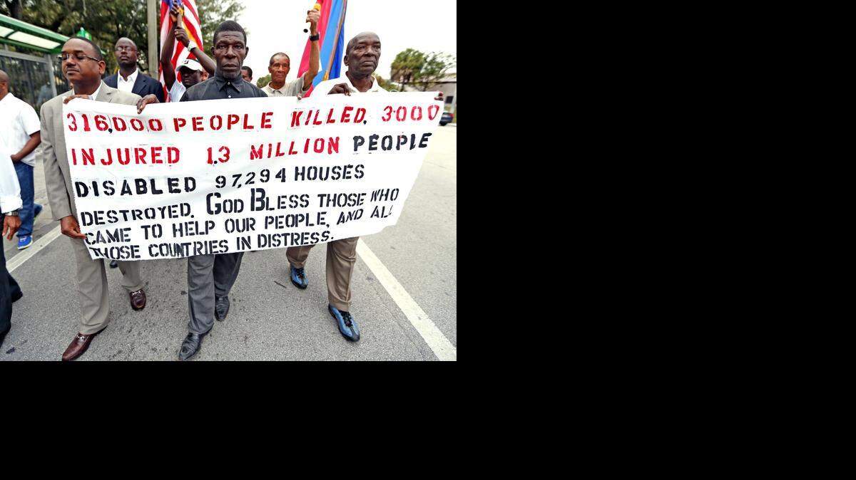 
Anis Blemur, Pasteur Germain and Cheker Bacho carry a banner marking the 5th anniversary of the 2010 earthquake that struck Haiti on January 12. 
