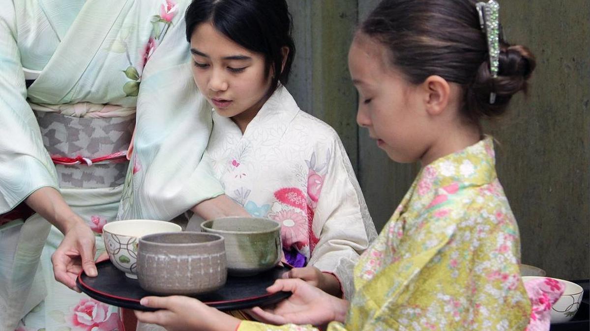 Yumi Nishimura, left, hands a tray of tea to Emma Crosa, center, 10, and her daughter Sophie Nishimura, 8, right, during the tea ceremony at the Ichimura Miami Japan Garden on Watson Island on Sunday, Jan. 10, 2016.