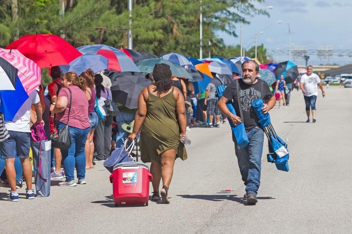 Cecil Umana, 64, walks past hundreds of people who are in line hoping to receive aid from a post-hurricane disaster center at Tropical Park in Miami on Sunday, Oct. 15, 2017.