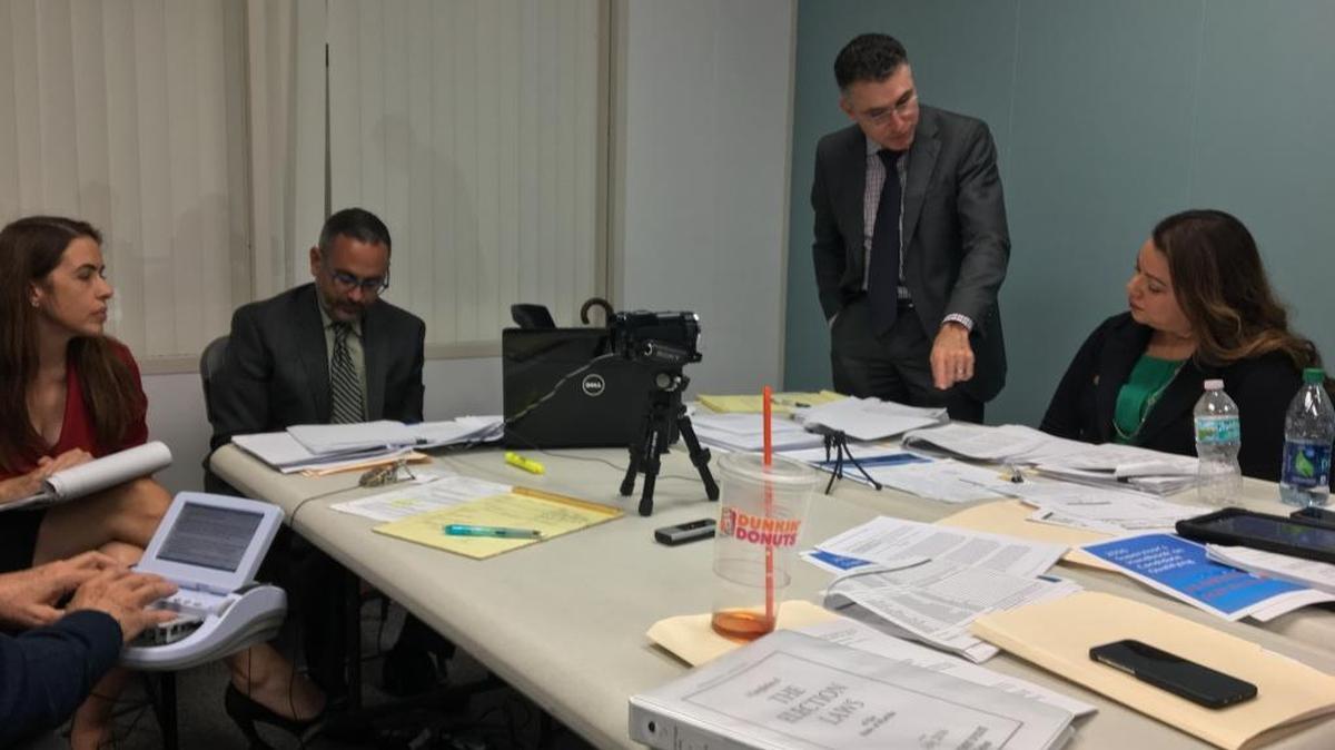 Raquel Regalado, far left, watches as her lawyer, Peter Gonzalez, standing, questions Carolina Lopez, deputy elections supervisor for Miami-Dade County, Saturday during a hastily arranged deposition on Regalado’s lawsuit against county Mayor Carlos Gimenez over alleged flaws in his qualifying check submitted in June. Seated to Regalado’s left is another attorney representing her, James Kellner.