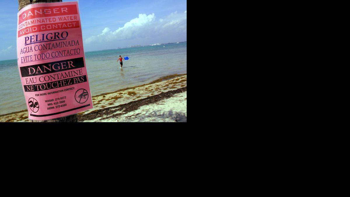 
A man washes his cooler at Hobie Beach in 2001 despite the signs warning of water contamination along the Rickenbacker Causeway after 12 million gallons of raw sewage spilled from a broken pipe at the mouth of the Miami River.

