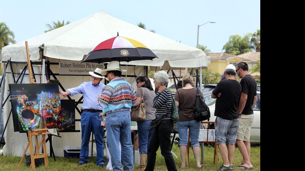 
Miami Springs photographer Robert Holmes, left, talks with Colley Billie, chairman of the Miccosukee Tribe of Indians of Florida, about how he created the "Gigapixel Panorama" photograph of downtown Miami at night, during the inaugural West End Art Fair on Saturday, April 18, 2015 in Miami's Kendall community. The IRS has won a key legal fight against the Miccosukee Tribe to collect potentially hundreds of millions of dollars in back taxes on casino income distributed to tribal members.

