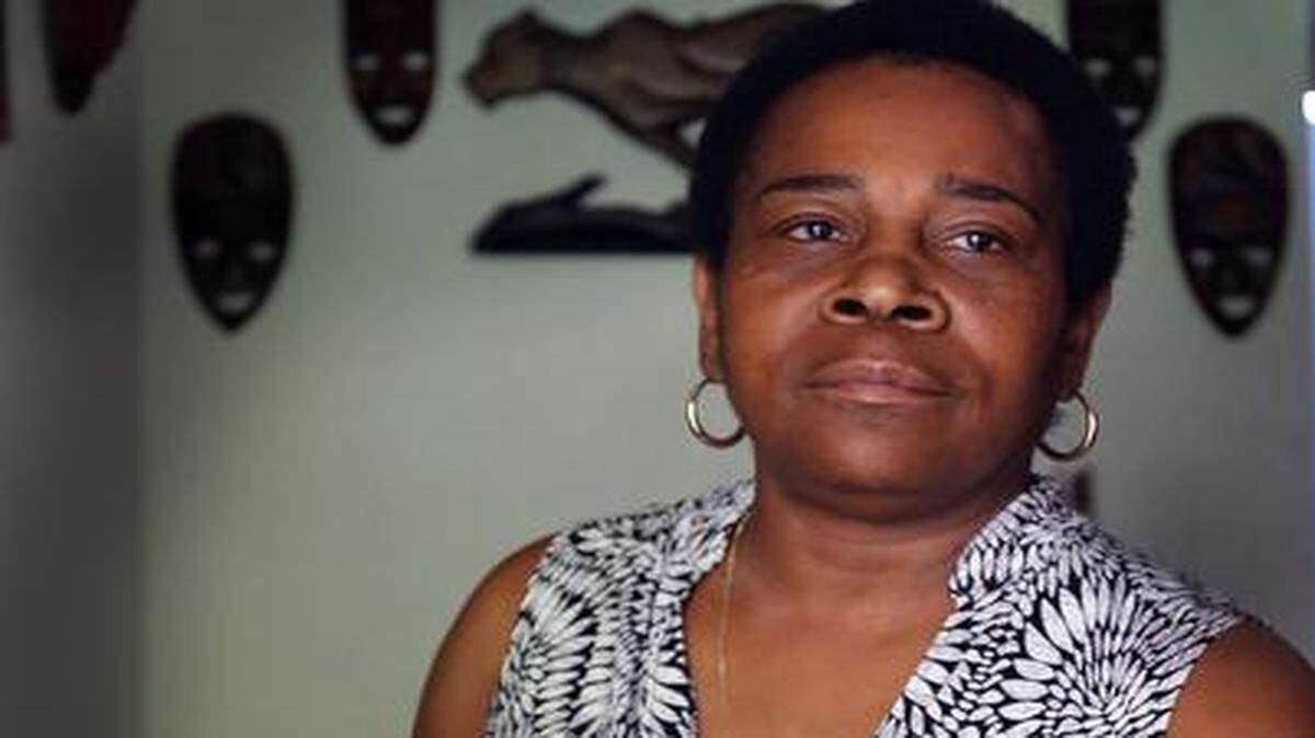 
Sheila McNeil, mother of Travis McNeil, an unarmed Miami man who was fatally shot by a police officer in 2011, holds on to a small portrait of her son while sitting in her livingroom in Overtown. McNeil’s shooting was among those reviewed by the Department of Justice. The city recently agreed to settle with McNeil’s estate for $1 million.
