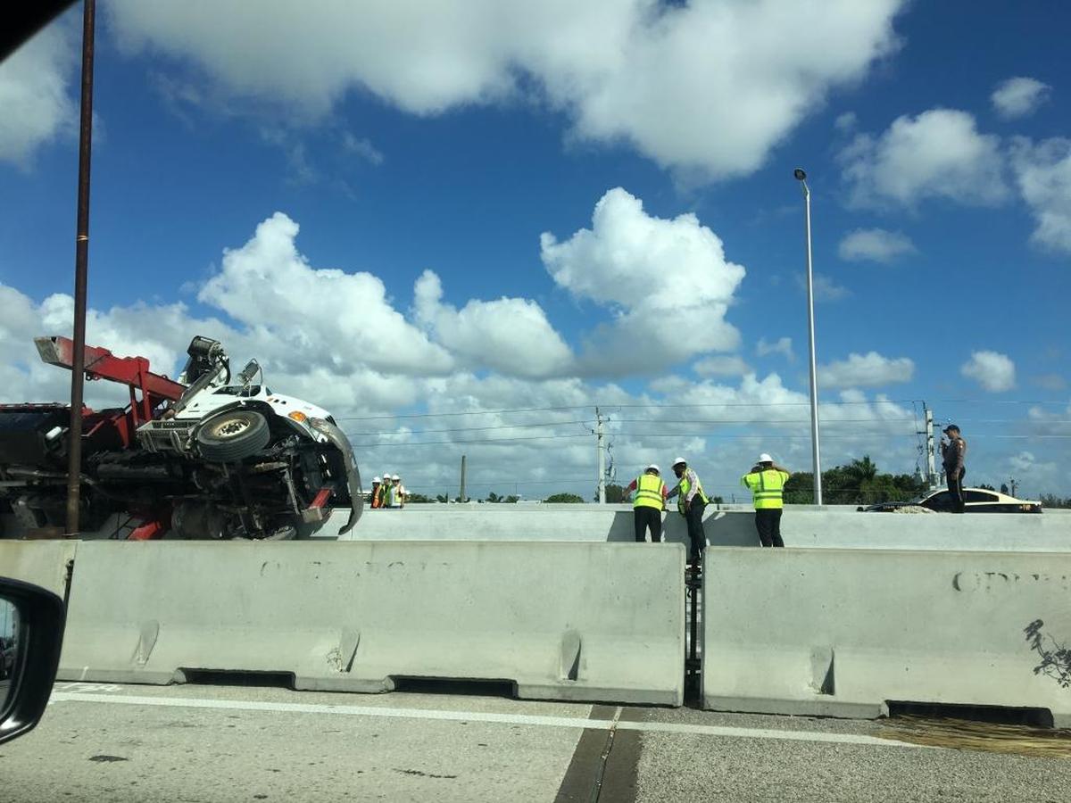 Workers look over the side of State Road 836 after an accident involving a truck and a construction worker on Wed., Oct. 11, 2017.