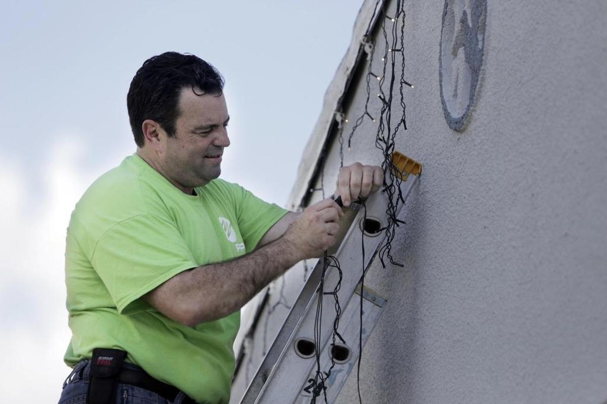 FPL’s Frank Cantero, a neighbor, installs lights at the home of Patrick and Ann McMullan on Tuesday, Dec. 5, 2017. McMullan is a retired Marine Corp. lieutenant colonel. Florida Power & Light transformed his home into an energy-efficient winter wonderland.