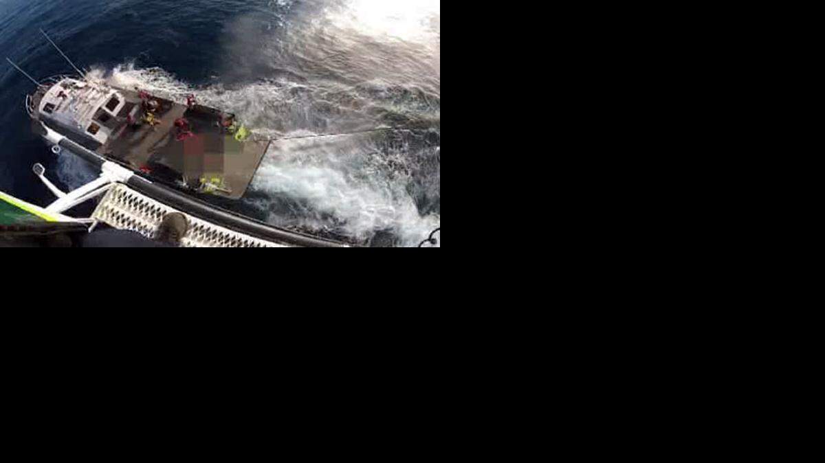 
A rescue crew assists a man after his boat capsized in rough waters.
