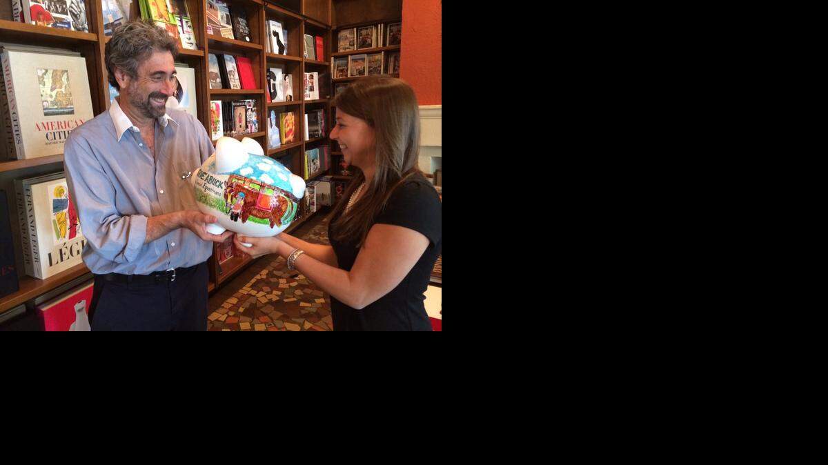 
Mitchell Kaplan of Books & Books receives the Give A Buck Piggy Bank from Mary Snow, Coral Gables Community Foundation executive director. Donations to the piggy banks raise funds for community causes. Coral Gables Senior High School art students painted the pigs. 

