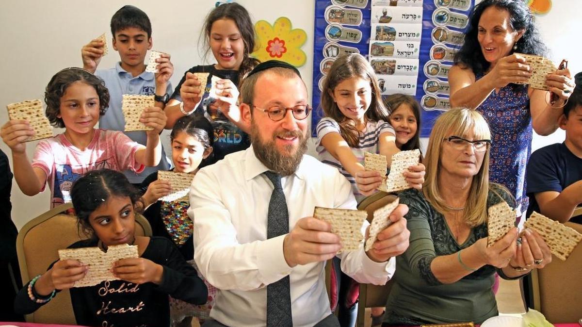 Rabbi Eliezer Wolf of Beit David Highland Lakes Shul breaks a matzoh with children during the Hebrew school's mock Seder, April 6, 2017. The children were asked questions about Passover and Hebrew studies. The shul is located in Northeast Miami-Dade.
