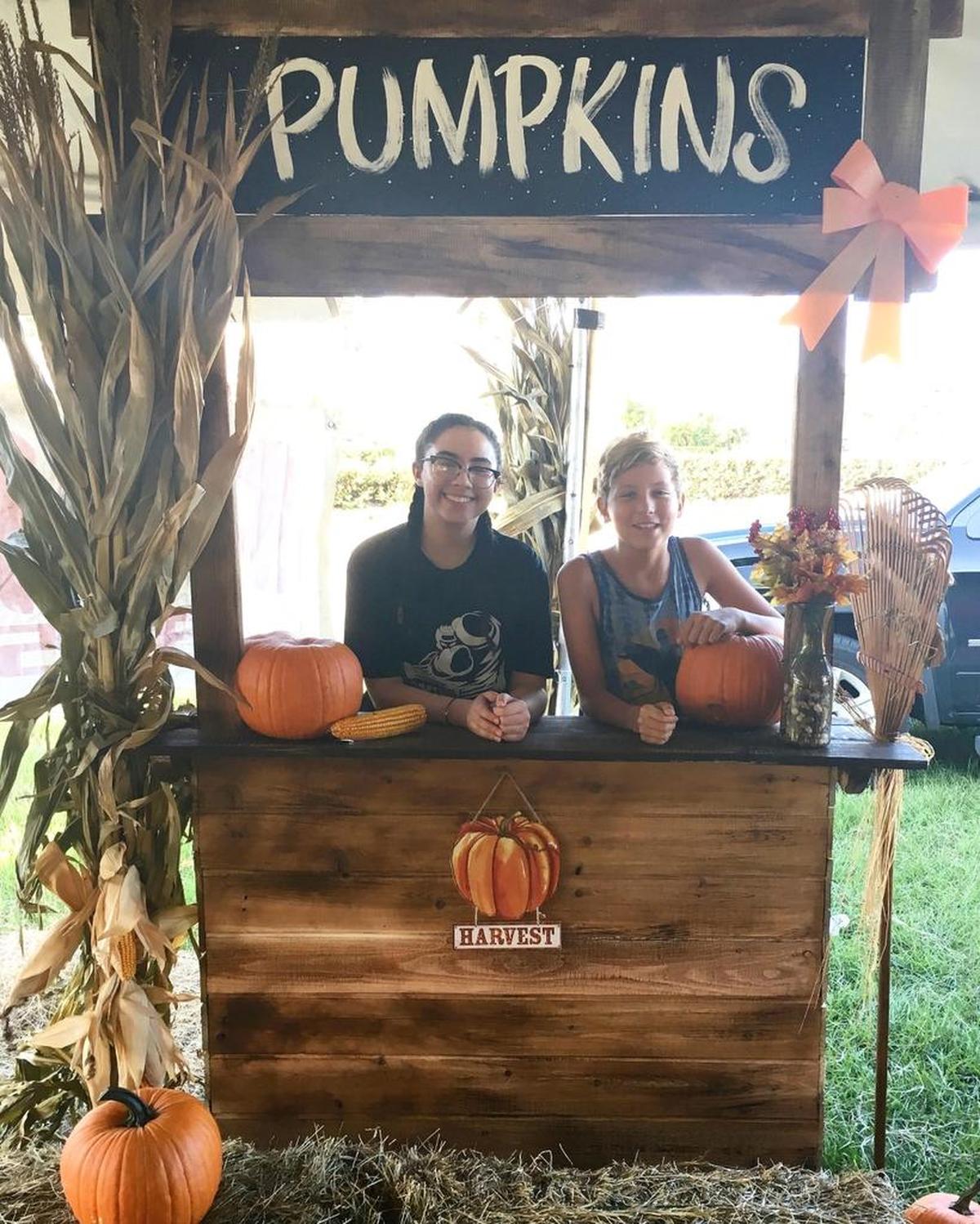 Aly Alonso and Tyler Pearce take care of a booth at the West Kendall Pumpkin Patch. The patch is open until Halloween for purchases and holiday photo opportunities.