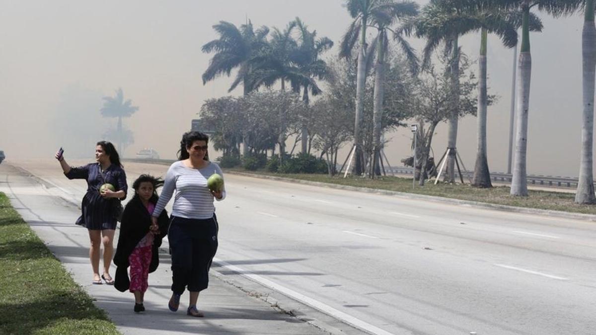 A family walks away from a brush fire Sunday, March 5, 2017, that shut down Southwest Eighth Street from 137th Avenue to Krome Avenue.