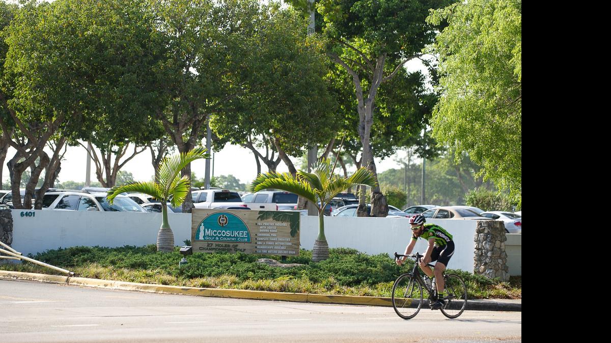 
A bicyclist rides along Kendale Lakes Drive, past Miccosukee Golf and Country Club, in Kendale Lakes. Some area residents worry they will lose say in zoning, policing, and maximum population density if the club becomes tribal land.
