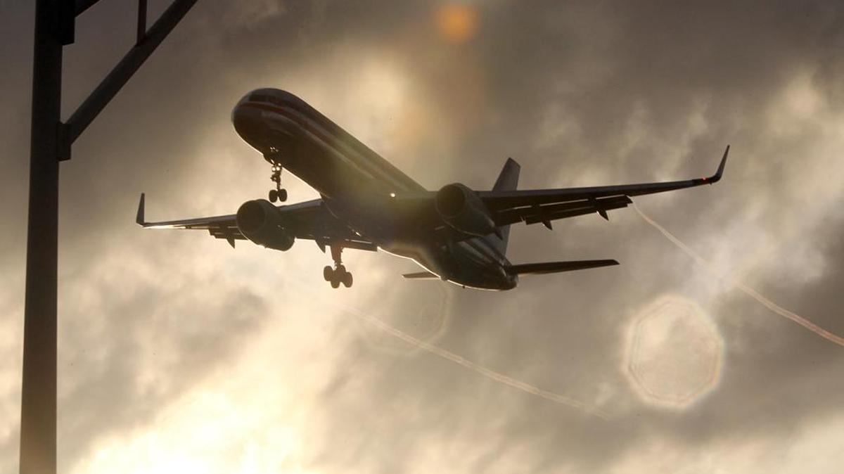 FILE--An American Airlines plane flies low through a cloudy sky as it gets ready to land at Miami International in Miami in this file photo. More than 200 passengers aboard an American Airlines jet met by the bomb squad at Miami International Airport because of “suspicious activity” were cleared and being taken to the gate Tuesday evening, according the airport.