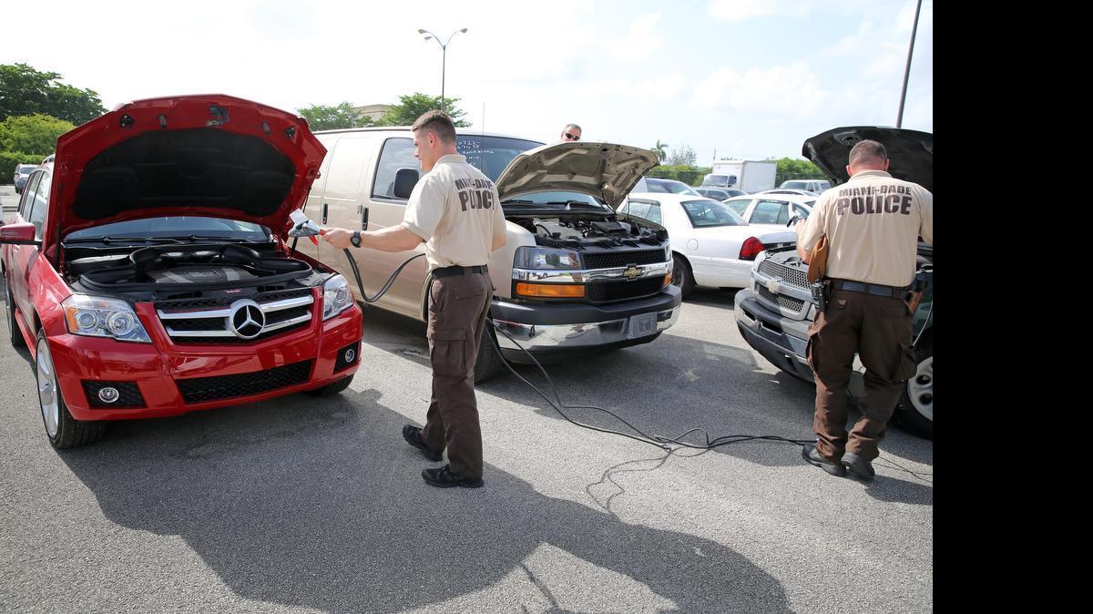 
Miami-Dade Police Officer Danny Llano prepares to jump start a 2010 Mercedes 350 GLK that is one of the vehicles the department has from forfeitures that are currently part of an online auction.
