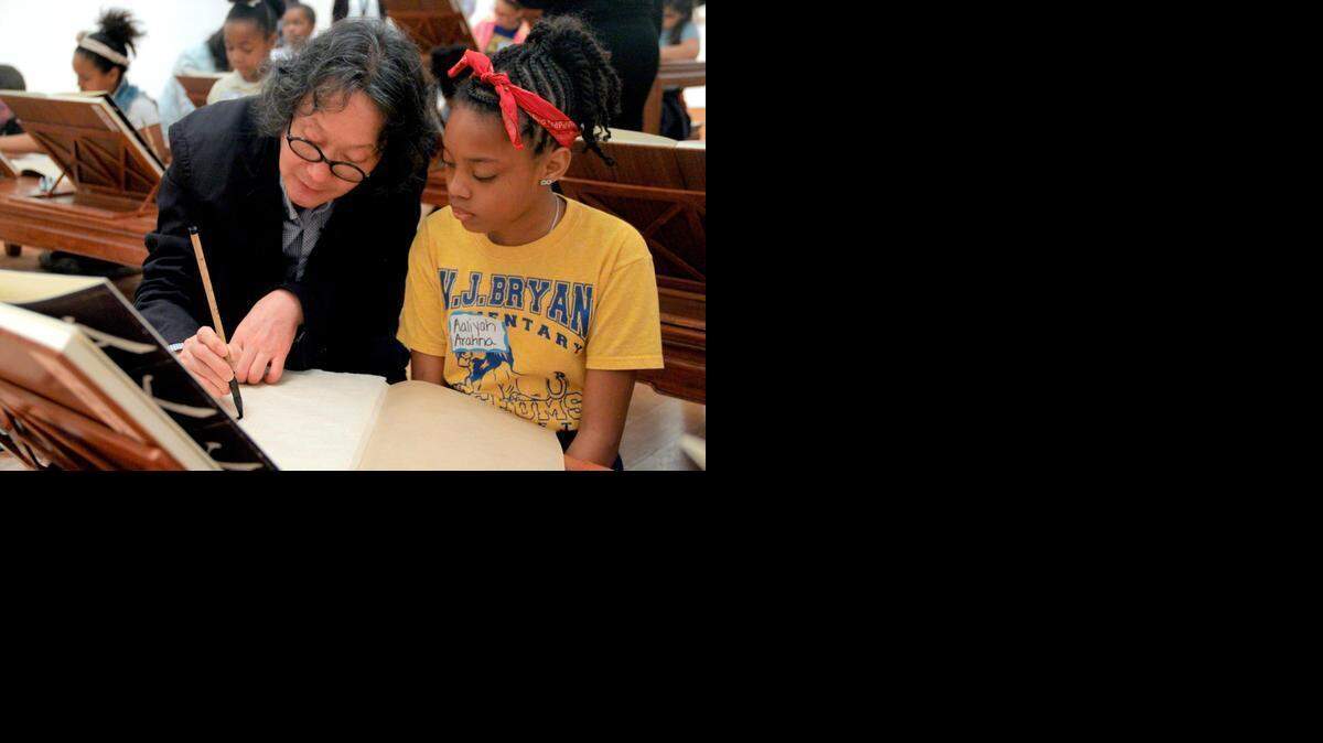 
Chinese art star Xu Bing, left, shows W.J. Bryan Museum Magnet School fifth grader Aaliya Arahna, right, how to do Chinese calligraphy. Fifth grade students visited the Patricia and Phillip Frost Museum at Florida International University to meet Chinese art star Xu Bing and participate in an interactive calligraphy workshop.
