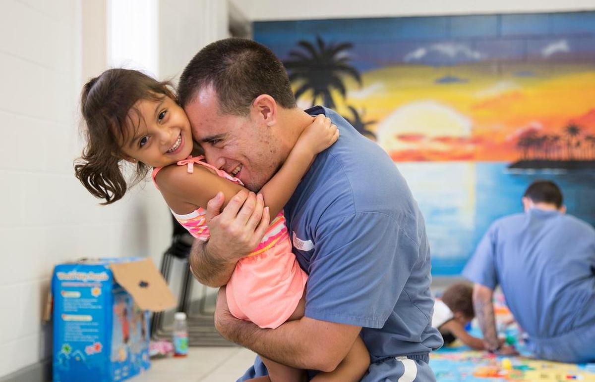In this 2015 file photo, an inmate and child share a happy moment during an event put on by Children of Inmates and the Florida Department of Corrections  at the Everglades Re-Entry Center.