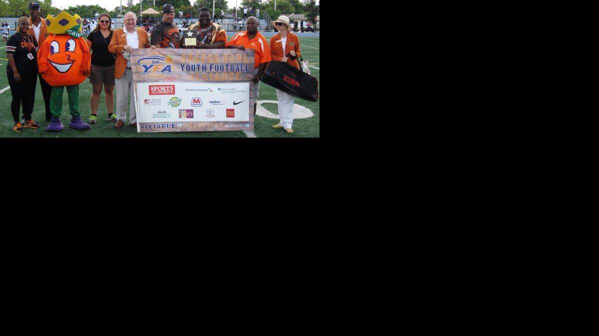 
The Orange Bowl Youth Football Alliance visited Betty T. Ferguson Recreational Complex, home of the Florida Youth Football League’s Miami Gardens Chiefs, as part of the Orange Bowl YFA Park of the Week Program. Pictured from left, Miami Gardens Chiefs Cheer Commissioner Monica Perry, OBC member Gerald Grant Jr., Orange Bowl mascot Obie, Sports Authority Community Marketing Representative Emily Perez, OBC member Ronald Albert Jr., Miami Gardens Chiefs Football Commissioner Rich Jospitre, Miami Gardens Chiefs 14U Coach Toro Rolle, OBC ambassador Gary Smith and OBC member Melissa Gracey.
