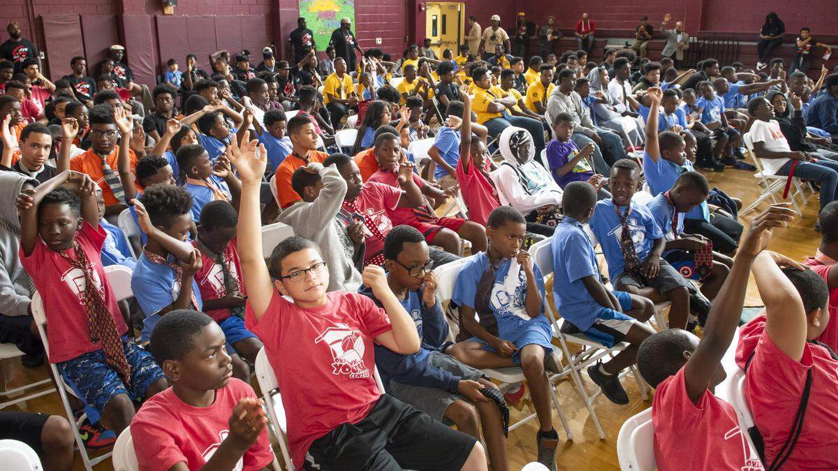 Young men raise their hands to answer questions at the Overtown Youth Center's Save Our Sons Youth Summit, which was created to develop and enhance the lives of young men predominantly in the Overtown area. The Summit provides mentors and young males an opportunity to build a bond grounded in support, success and achievement.