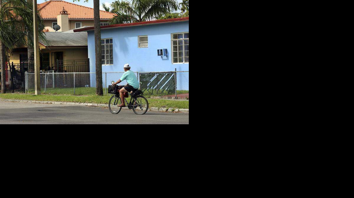 
A man bicycles past the New Greenview II assisted living facility home in Miami earlier this month. The ALF, which encompasses two houses at 2650 NW 15th Ave., concerns neighbors, who have long complained about its mentally ill residents. Miami-Dade prosecutors recently filed a murder charge against a paranoid schizophrenic man accused of fatally stabbing another man in the throat while on the property. 
