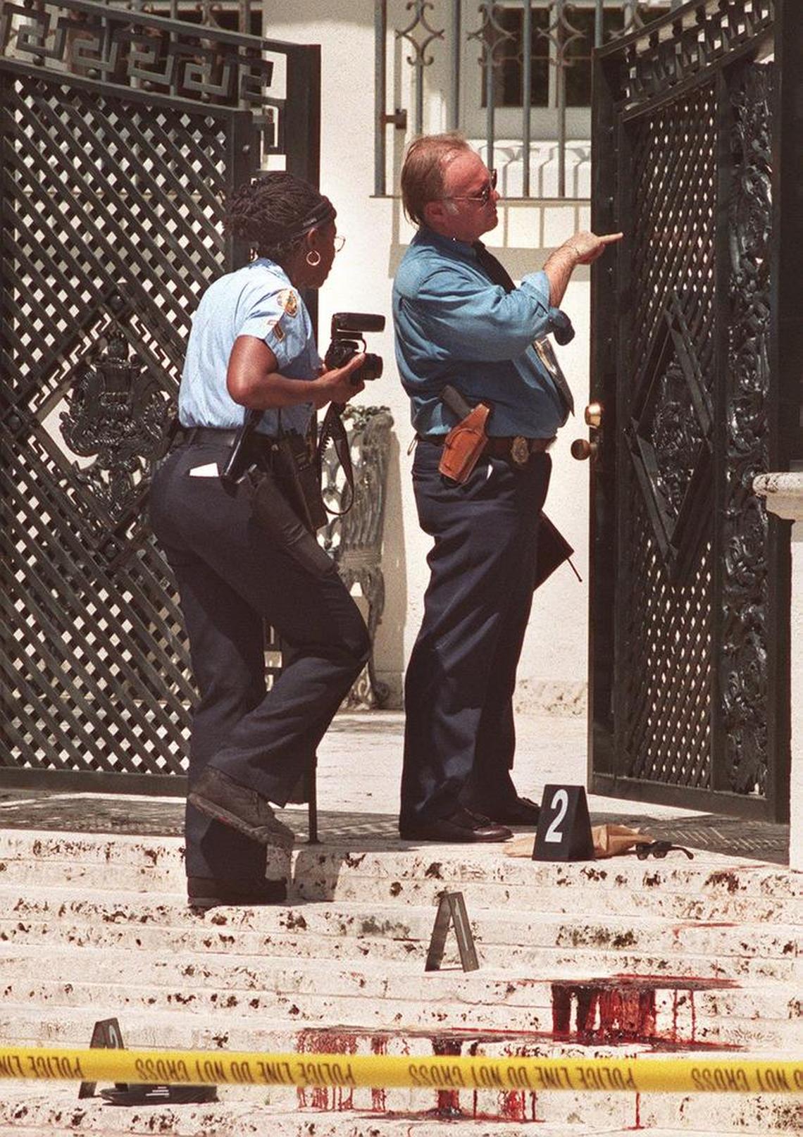 Police investigate the bloody steps and gate in front of Gianni Versace's house on Ocean Drive in Miami Beach, where the designer was gunned down by a suspected serial killer on July 15, 1997. The man on the right is the late lead detective on the Versace murder, Paul Scrimshaw.
