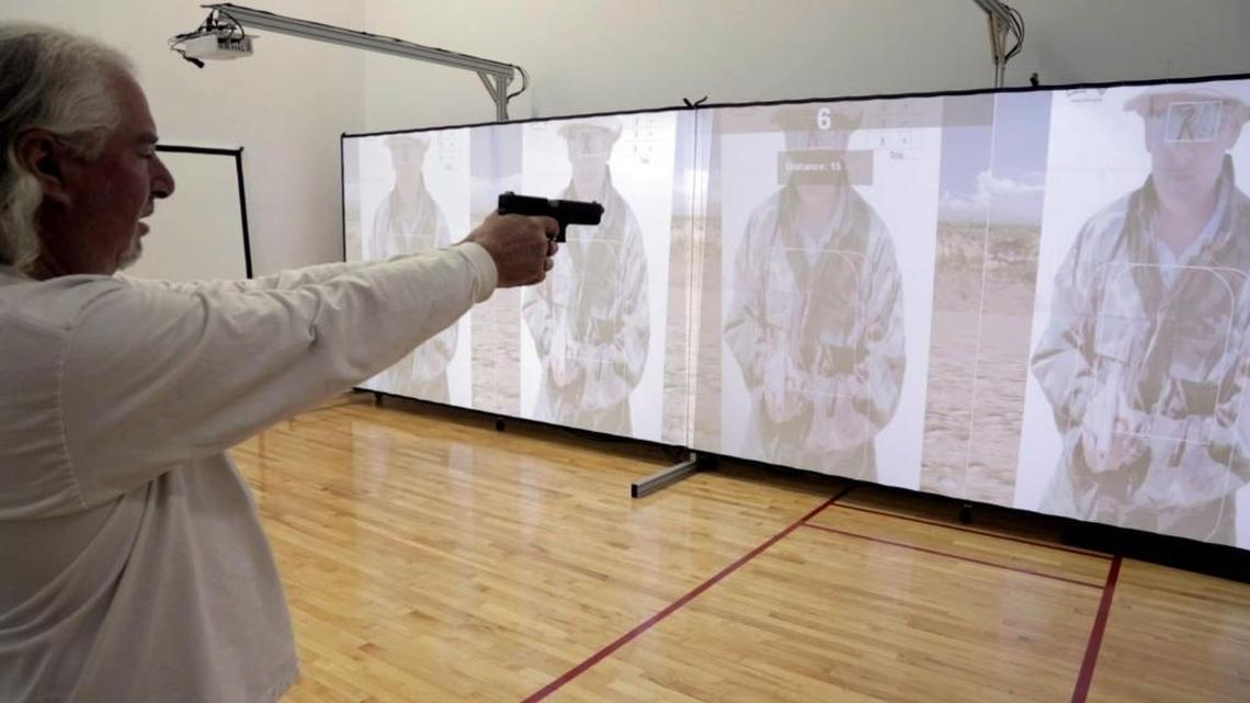 Miami Herald reporter Chuck Rabin tries out the simulator using a Glock pistol with a recoil kit designed to be used in simulators at the Miami-Dade police firearms training facility.