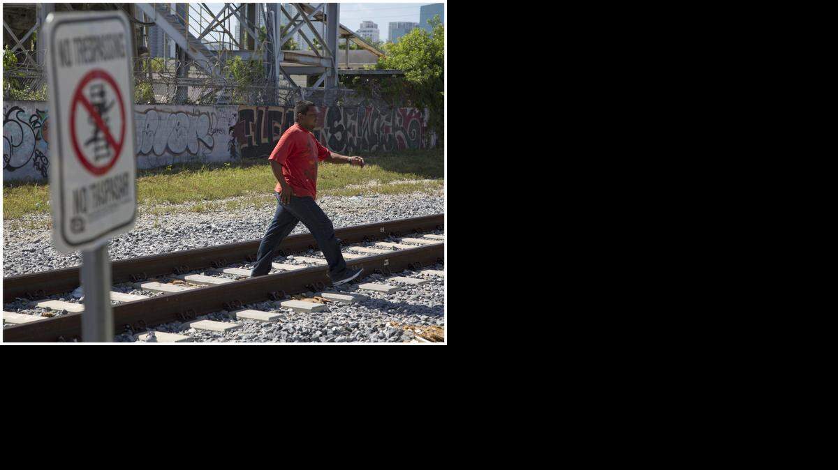 
Locals cross over the train tracks in the 100 block of Northwest 17th Street. Residents complain that Florida East Coast railway police are harassing and arresting them as they try to walk across the streets.
