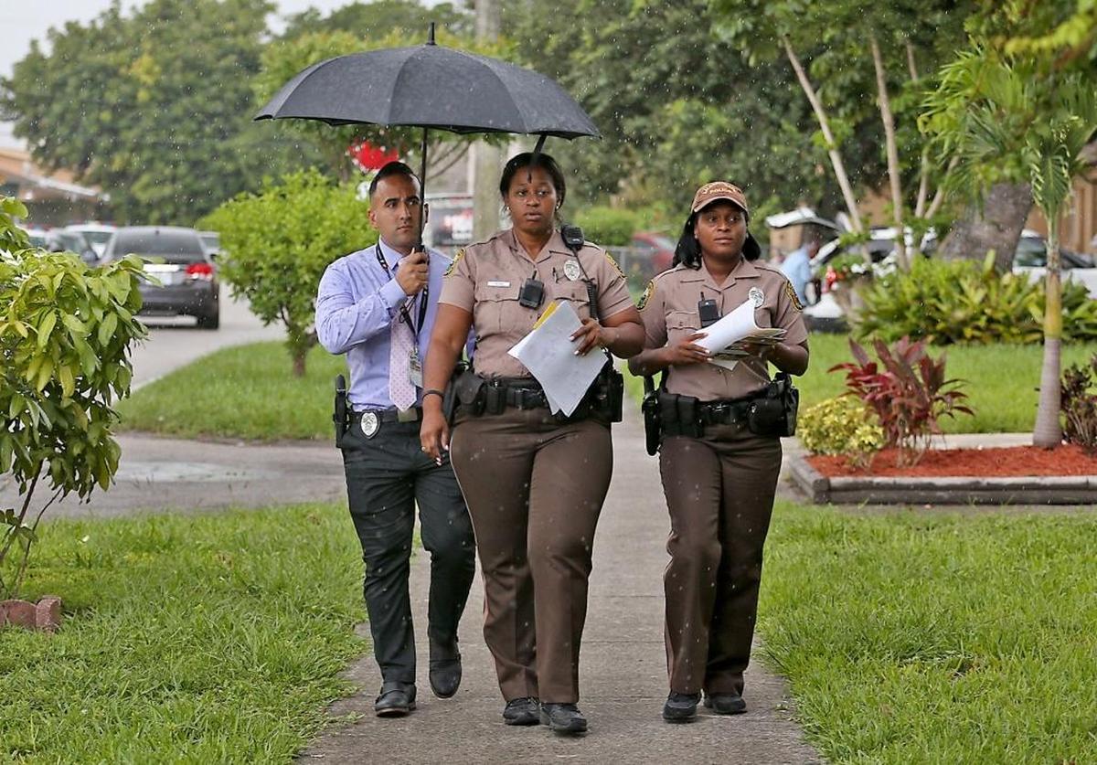 Miami-Dade Police detective Argemis Colome (left), Officer Camille Normil, and Officer Dominique Narcisse pass out fliers Thursday, July 20, 2017 to find out more info about the murder of 19-year-old Juwan Downes, who was shot and killed last Thursday evening.