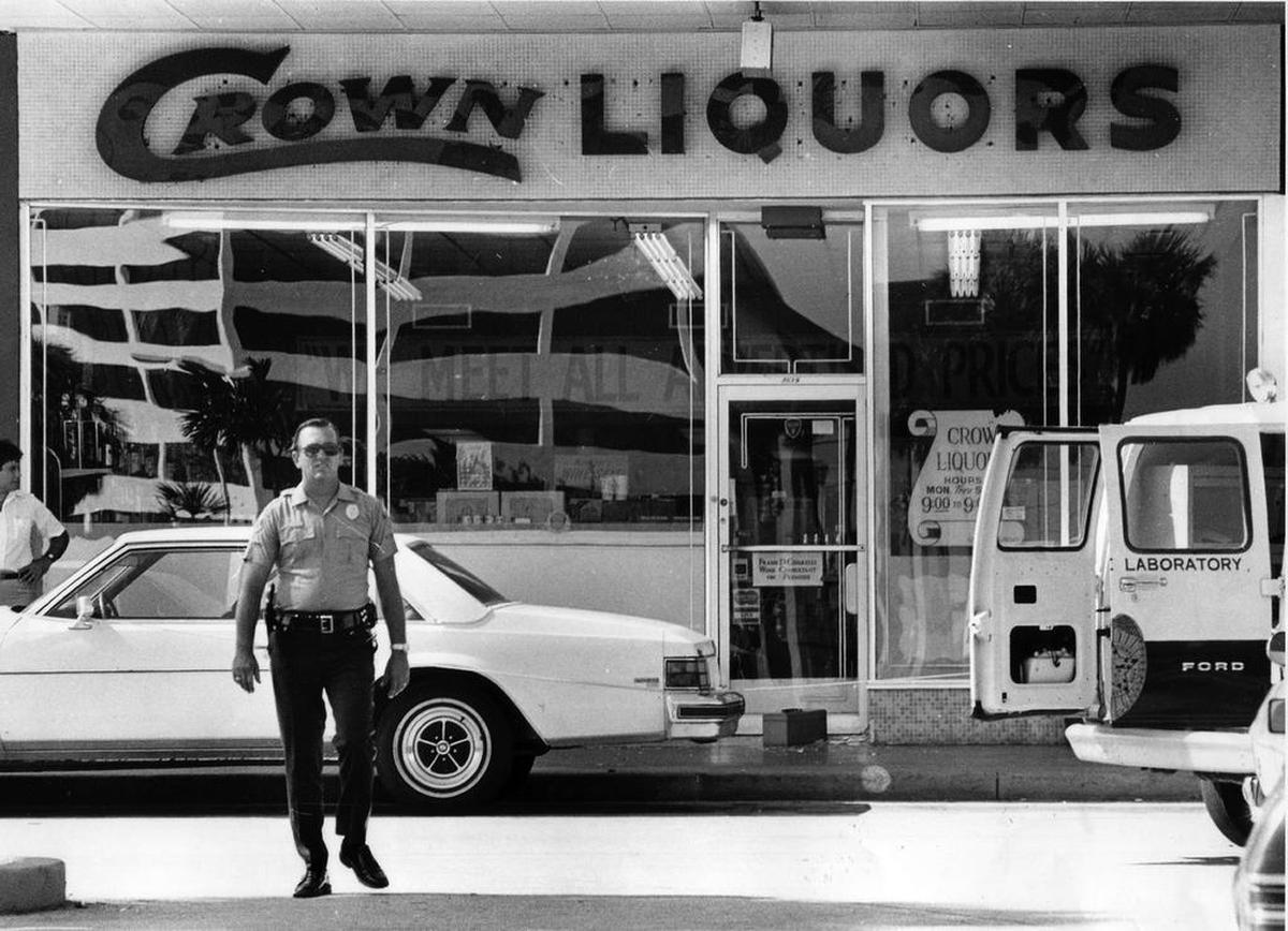 A Miami-Dade police officer investigates the scene in the parking lot of Dadeland Mall on July 11, 1979. The Crown Liquor store was the site of a Cocaine Cowboys hit. A Colombian drug lord and his bodyguard were shot by two men who sprayed the store with bullets and fired into the parking lot on a sunny Kendall afternoon in the suburbs.