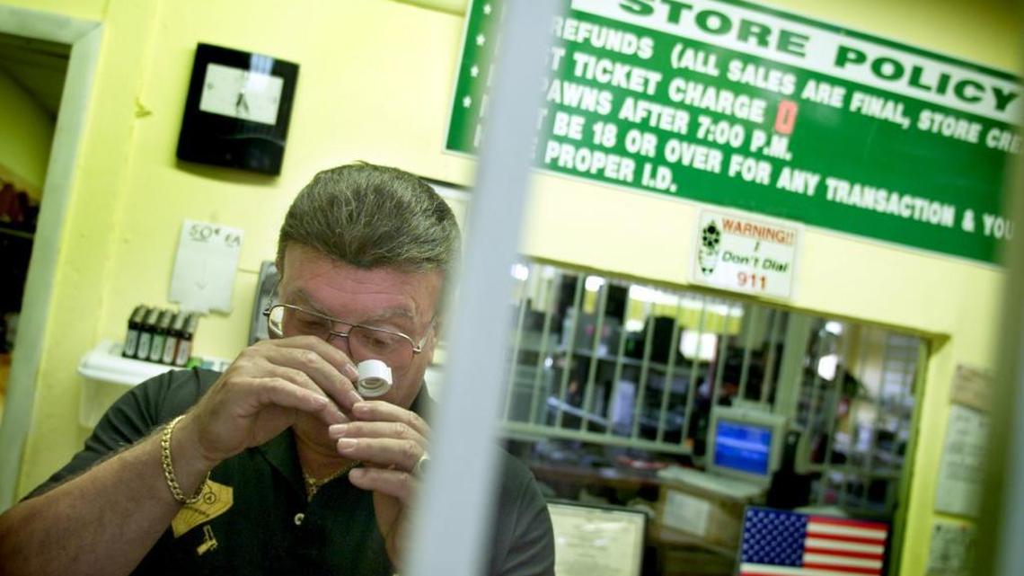 Martin Sprung, owner of AAA Pawnbrokers of North Miami, inspects a piece of jewelry in 2003. He was shot to death in 2008. His accused killer, Stevenson Charles, is on trial for murder.