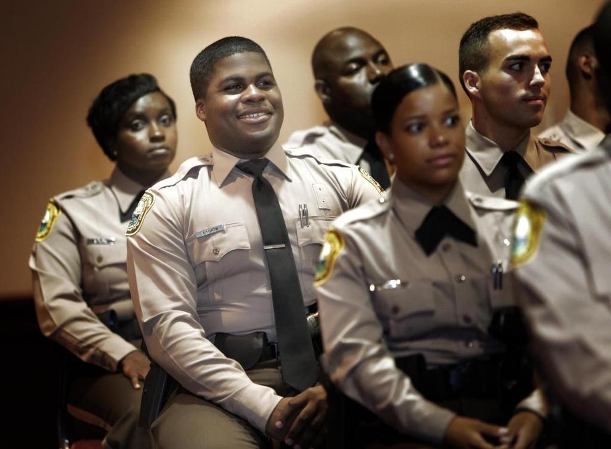 Andre Martin, second from left, sits with fellow Police Academy Graduates during the graduation ceremony. Thursday morning, Martin, a 26-year-old martial arts expert with a fiance and a child, was part of the new graduating class of Miami-Dade police.