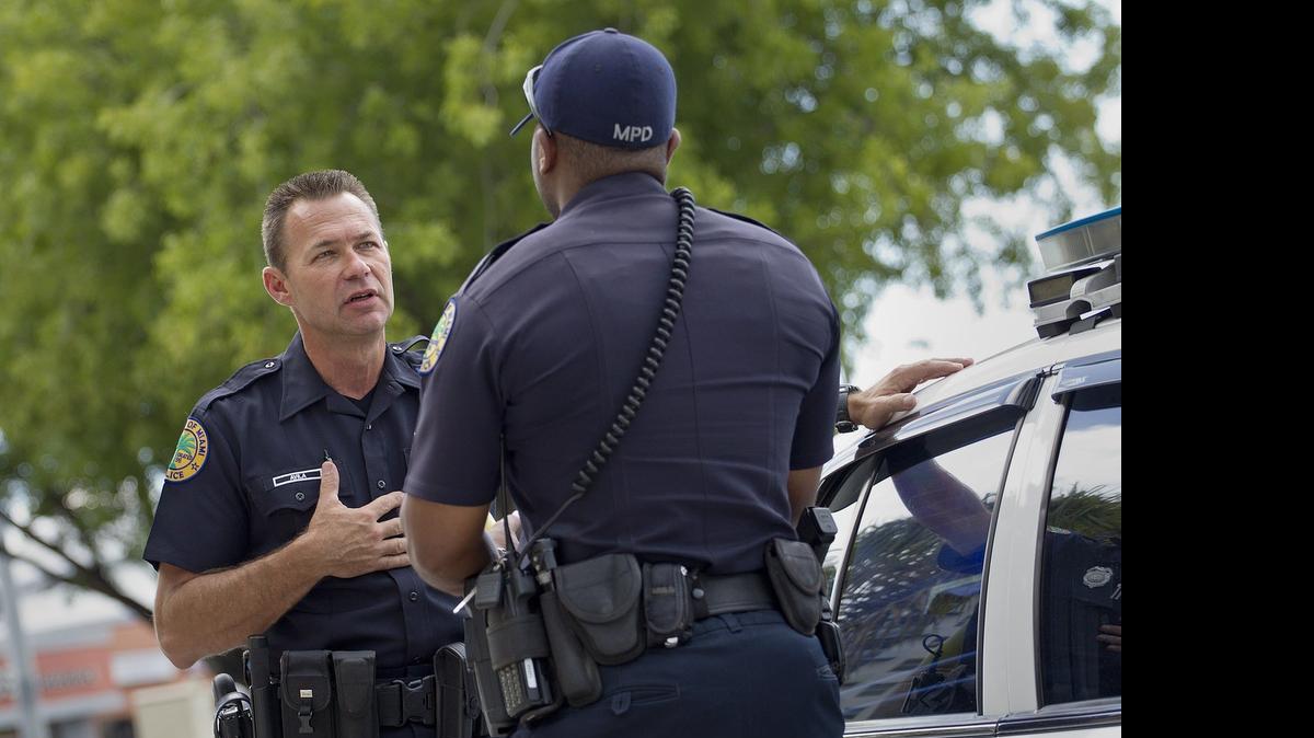 COMFORTING WORDS:  Officer Jorge Avila, a Miami Police Department chaplain and patrol officer, doles out advice to fellow cops in need.