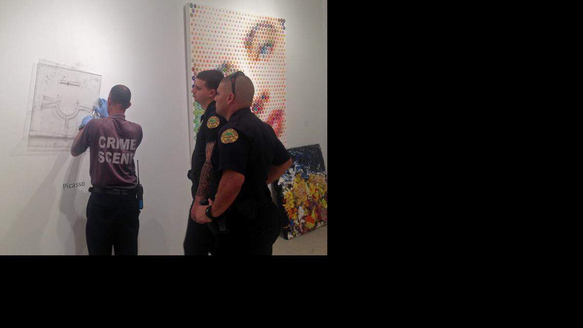 
Miami Police Department officers on Friday afternoon, Dec. 5, 2014, inspect the site from which a Pablo Picasso plate titled 'Visage aux Mains' was stolen. The framed silver plate, valued at about $85,000, went missing from the Leslie Smith Gallery housed within the massive Art Miami tent in Midtown.
