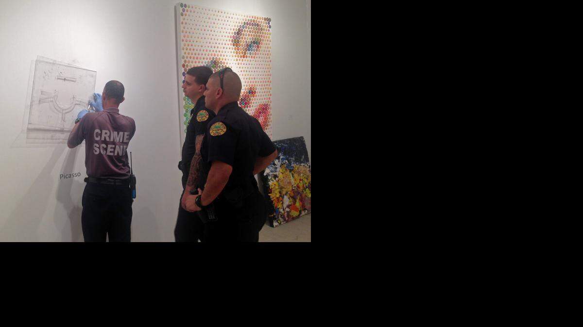 
Miami Police Department officers on Friday afternoon, Dec. 5, 2014, inspect the site from which a Pablo Picasso plate titled 'Visage aux Mains' was stolen. The framed silver plate, valued at about $85,000, went missing from the Leslie Smith Gallery housed within the massive Art Miami tent in Midtown.
