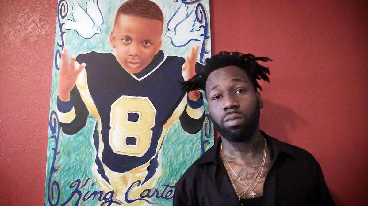 Santonio Carter, who has become active with Miami’s youth since the death of his 6-year-old son, poses in front of a picture of King Carter in his football uniform.