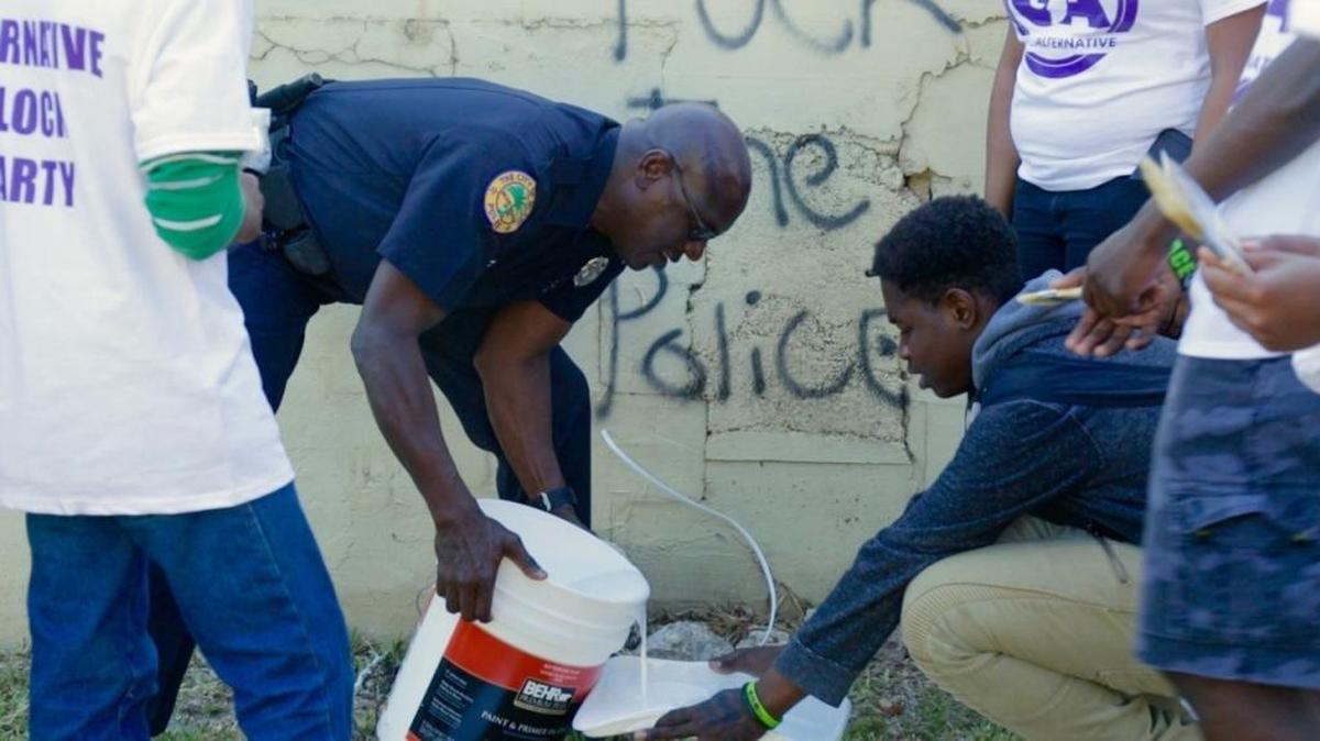 Miami Police Officer Wesner Moise alongside neighborhood youth from Gang Alternative reclaim a graffiti-covered wall by painting an art mural for their Little Haiti neighborhood.