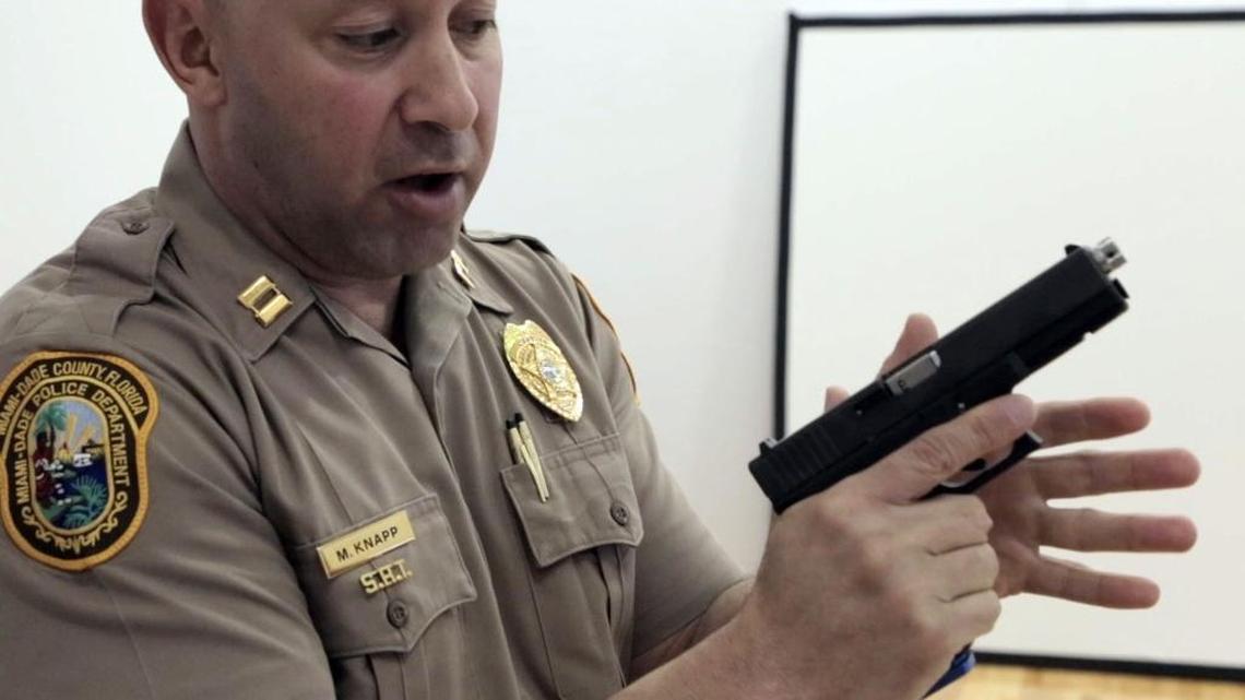 Miami-Dade Police Capt. Mario Knapp, demonstrates proper hold of a weapon using a Glock pistol with a recoil kit designed to be used in simulators at the Miami-Dade police firearms training facility in Doral.