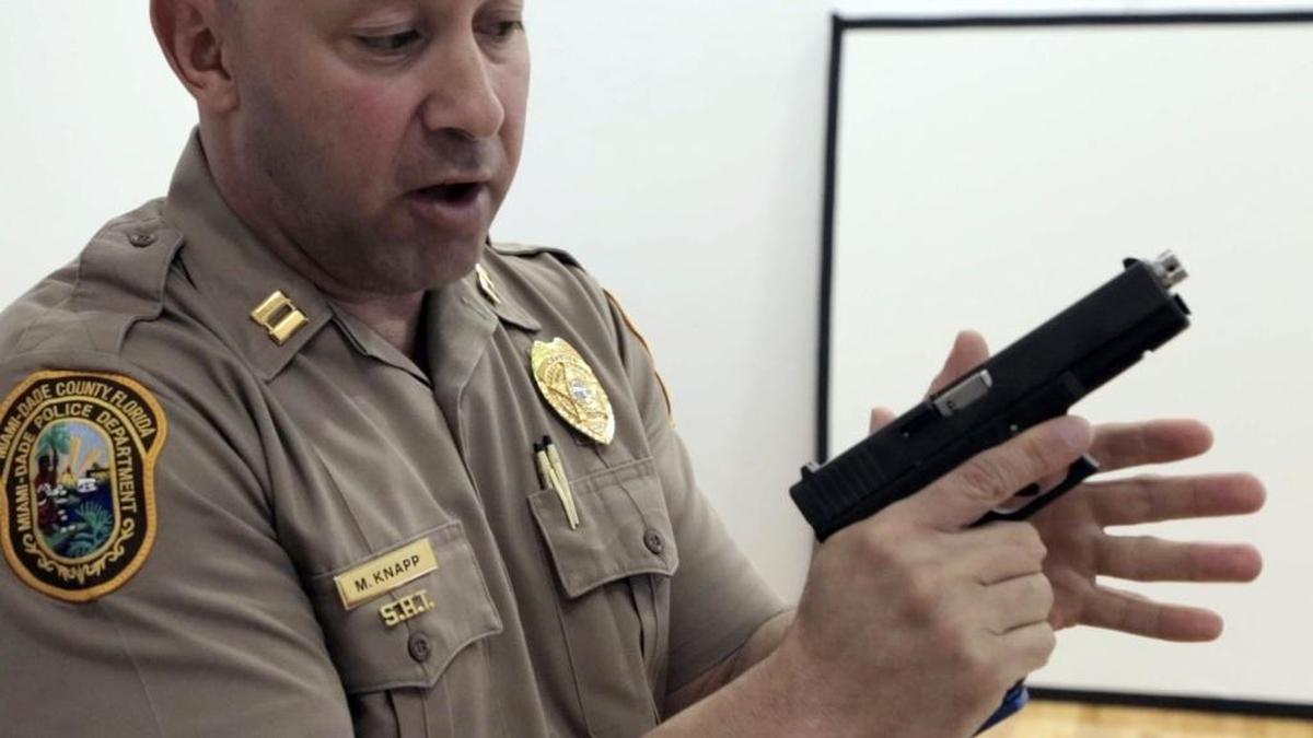 Miami-Dade Police Capt. Mario Knapp, demonstrates proper hold of a weapon using a Glock pistol with a recoil kit designed to be used in simulators at the Miami-Dade police firearms training facility in Doral.