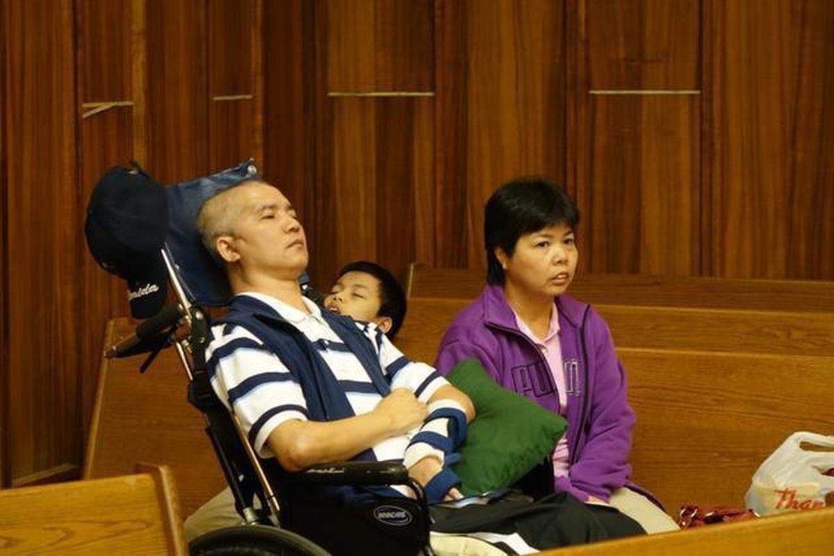 Miami store clerk Yue Kui Cen, in a wheelchair and unable to talk after a December 2011 hammer attack, in court alongside his wife.