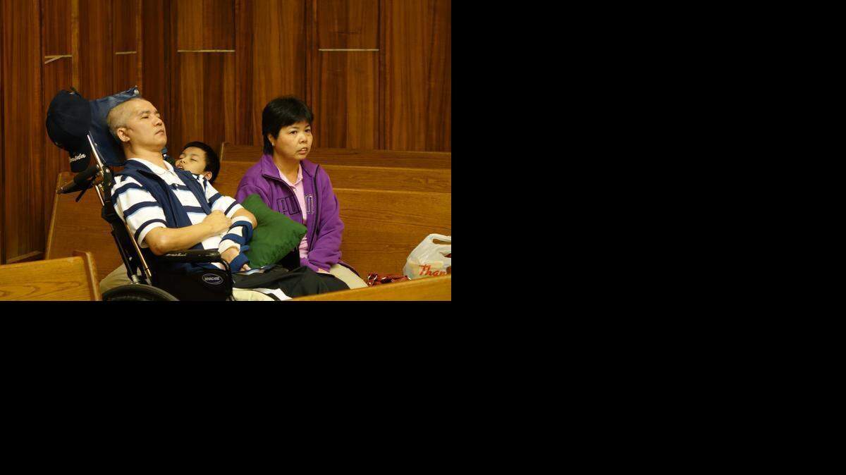 
Miami store clerk Yui Kui Cen, in a wheelchair and unable to talk after a December 2011 hammer attack, in court Friday alongside his wife.
