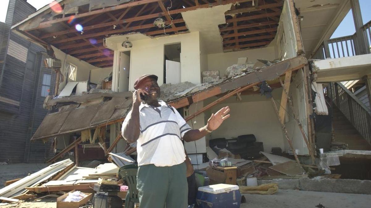 In this file photo, a hurricane victim talks on his cellphone to a Red Cross official as he tries to recover belongings from his destroyed ground floor apartment.