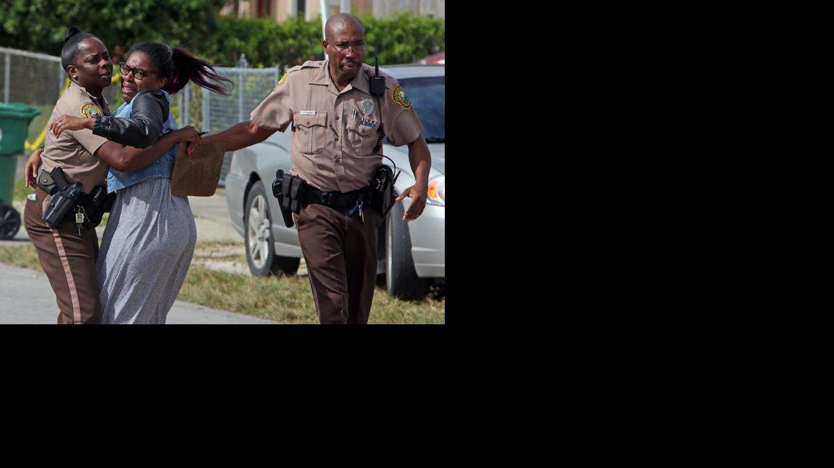 
A woman is restrained by Miami-Dade police officers in the 2400 block of Northwest 90th Street from entering the crime scene area where a woman was killed on Tuesday Nov. 25, 2014.
