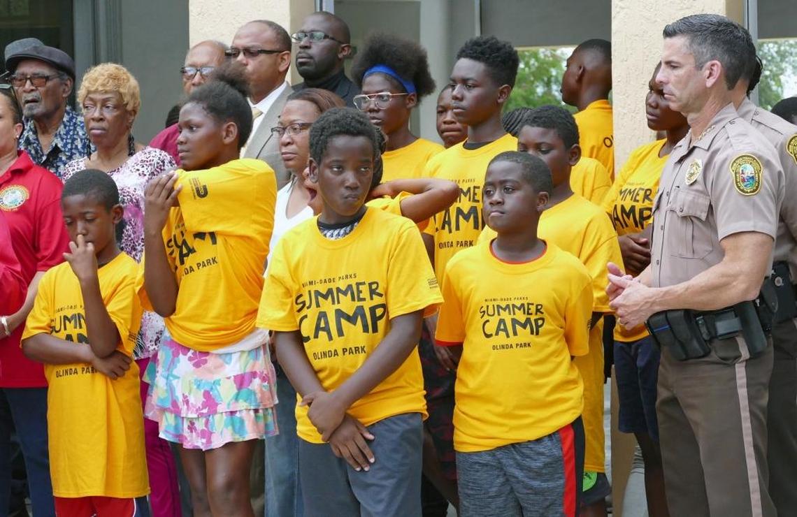 Miami-Dade Police Director Juan Perez, right, stands next to children while Miami-Dade Commission Vice Chairwoman Audrey Edmonson holds her annual "One Bullet Kills the Party" news conference at Jefferson Reeves Sr. Park in Miami to urge the public from celebratory gun usage Fourth of July.
