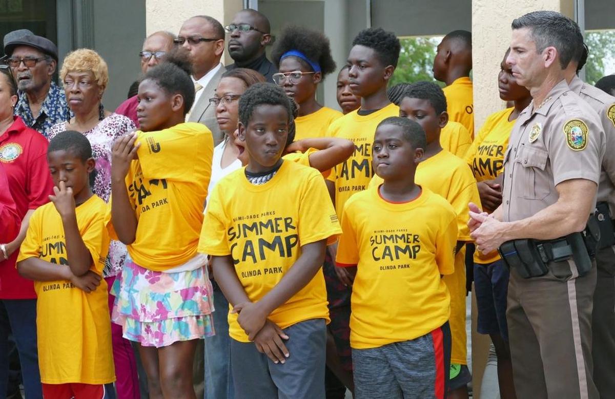 Miami-Dade Police Director Juan Perez, right, stands next to children while Miami-Dade Commission Vice Chairwoman Audrey Edmonson holds her annual "One Bullet Kills the Party" news conference at Jefferson Reeves Sr. Park in Miami to urge the public from celebratory gun usage Fourth of July.