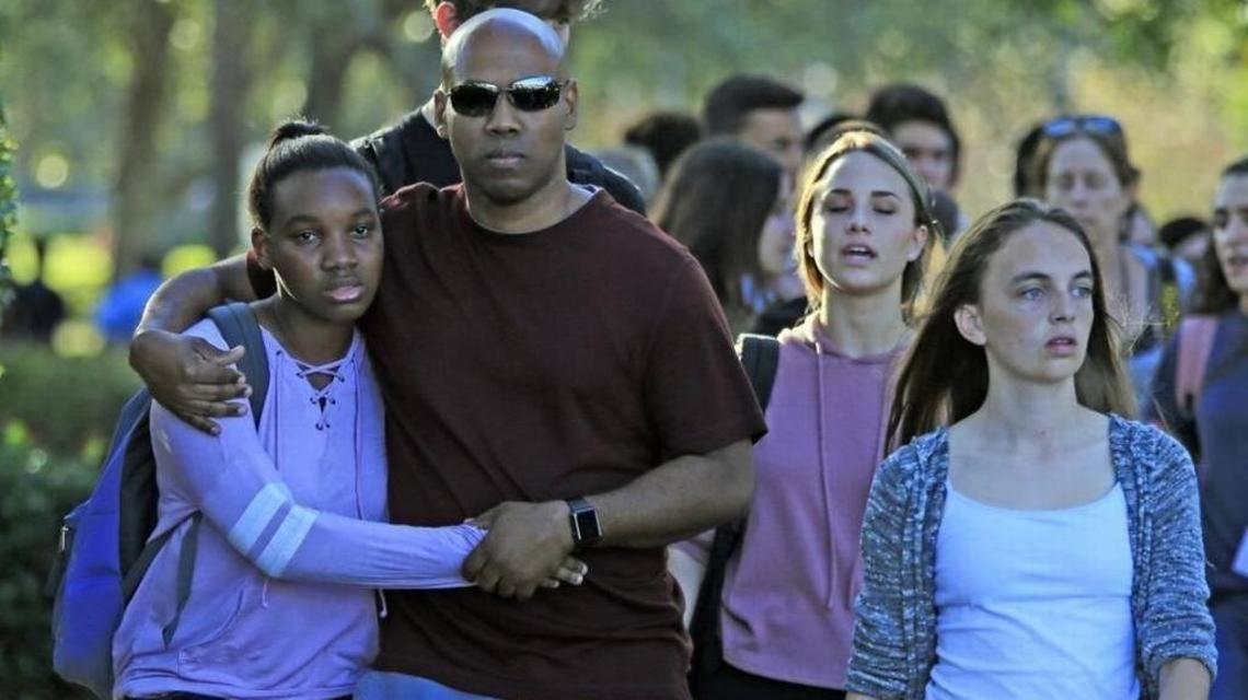 Students and parents walk away from the campus of Marjory Stoneman Douglas High School after a mass shooting.